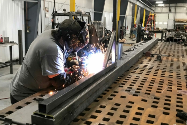 A BoxPop employee welding a custom shipping container